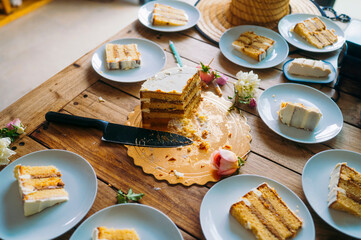 Half-eaten layered cake on wooden table with plates.