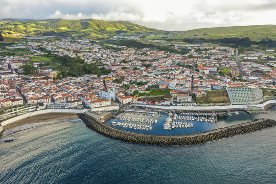 Aerial view of the cityscape blending into the coast with boats docked near the breakwater, Angra do HeroÃ­smo, Azores, Portugal.