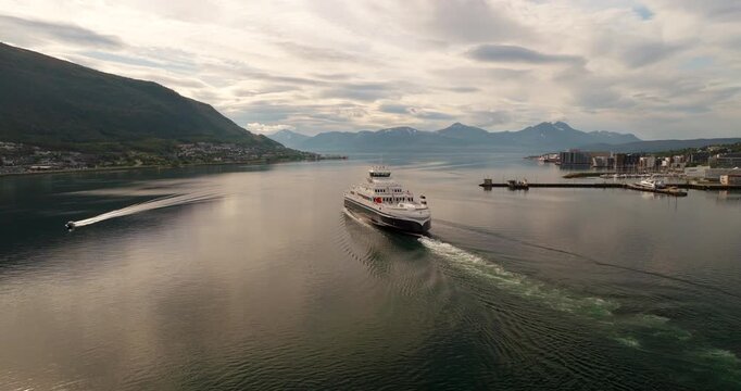 Fully electric MF Hinn&oslash;y ferry departs Tromso coastline in summer, rear aerial