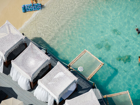 Aerial view of sun-drenched cabanas line the turquoise water, where swimmers enjoy the crystal-clear depths, Ksamil, Vlor, Albania.