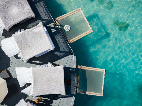 Aerial view of sunbeds casting deep shadows against the turquoise water, a serene contrast of textures and tones, Ksamil, Vlor, Albania.