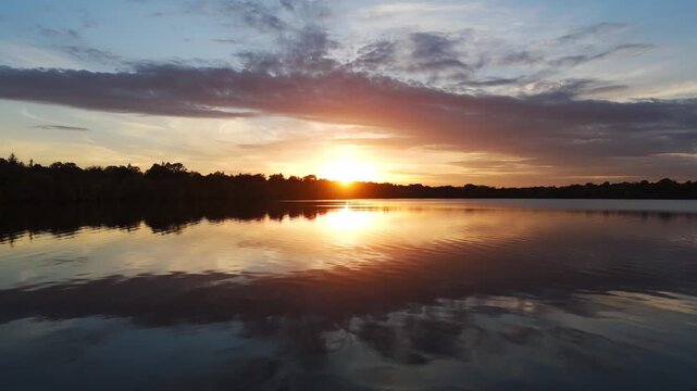 The lake Calhound Vde Maka Ska glows under a vivid sunset, colors strikingly bright against the dark silhouette of distant shores.