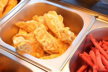 Delicious fried wontons served in a restaurant buffet alongside red-colored fries