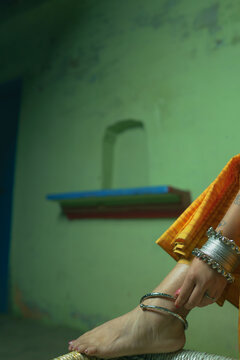 Feet of an Indian woman embrassing her look in Indian Saree attire with Bangles and Anklet as jewellery.

