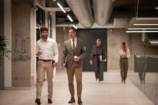 Business colleagues walking and talking in modern office hallway