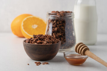 Chocolate granola with almonds in a wooden bowl close-up view on white background with copy space. Healthy breakfast concept