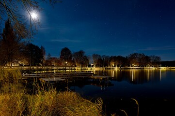 Night view of the bathing pier and the illuminated dam of the Str&aacute;ž pond in Pelhřimov, autumn, dry grass