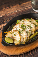 Grilled sea bass fillet served on skillet with vegetables