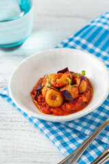 Cooked shrimp in rich tomato sauce served in white bowl