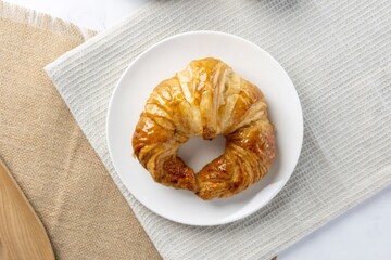 Golden croissant pastry serving on a white plate