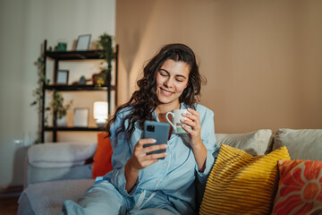Young woman enjoying a cozy morning at home with coffee and smartphone