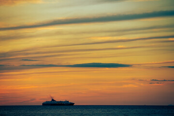 A ferry silhouette against a stunning orange and yellow sunset