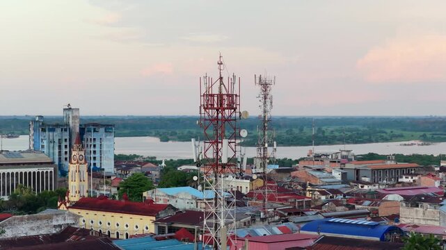 Communication towers stand over the rooftops of Iquitos, largest city in the Peruvian Amazon. Distant river in the background