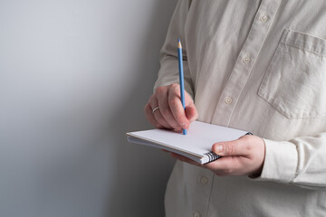 Woman writing notes in a notebook. Close-up of hands holding a notebook and writing with a pen....