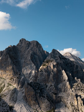 Aerial view of rugged, grey peaks rise sharply against a clear blue sky, their rocky faces etched with shadows and light, Teth, Shkoder County, Albania.