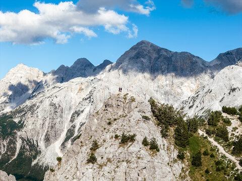 Aerial view of rugged, sun-drenched mountains pierce the azure sky, their rocky faces softened by patches of green, a testament to nature's resilience, Teth, Shkoder County, Albania.