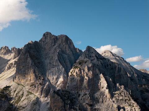 Aerial view of jagged, rocky mountains pierce the clear blue sky, their slopes etched with light and shadow, Teth, Shkoder County, Albania.