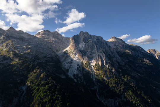 Aerial view of jagged peaks rise majestically against the sky, their rocky faces kissed by sunlight and shadowed valleys, Teth, Shkoder County, Albania.