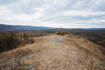 Peaceful plateau with distant forest view, Quiet elevated terrain featuring gentle hills and overcast sky, Serene highland landscape offering views of fields and distant wooded horizons