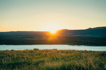 Sunset reflecting on water, creating a picturesque mountain backdrop scene.