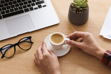 Woman having coffee break at wooden desk, closeup