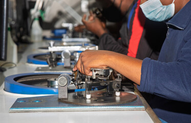 two african workers, diamond polisher at work, using a polishing wheel to shape and refine a rough diamond, brillianteering