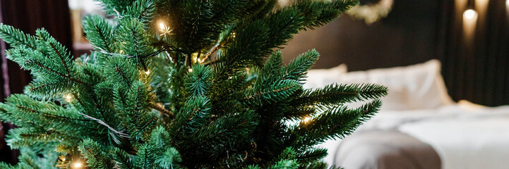 Obraz premium Bedroom interior decorated for Christmas holidays. Home interior with a Christmas tree on a dark wall background.