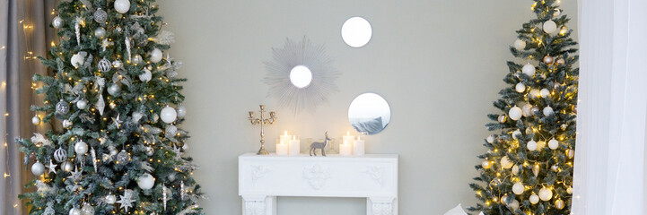 Bright interior with a false fireplace decorated for Christmas. Christmas trees with garlands,...