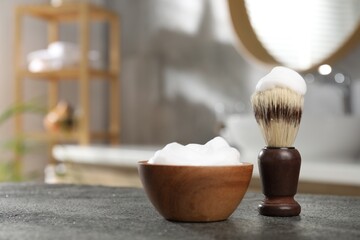 Shaving brush and foam on grey textured table indoors, closeup with space for text. Barber's tools