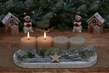 Second Advent: Natural Advent decoration with fir branches and beige candles in front of a Christmas background with space for text.
