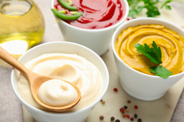 Different sauces, spices and herbs on light table, closeup