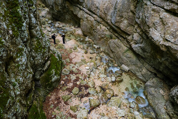 Hikers exploring rocky mountain canyon with stream