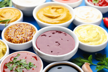 Different sauces and herbs on blue background, closeup