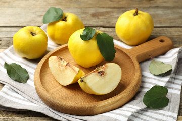 Whole and cut ripe quinces on wooden table, closeup