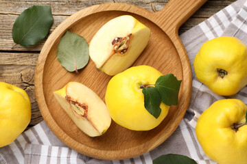 Whole and cut ripe quinces on wooden table, flat lay