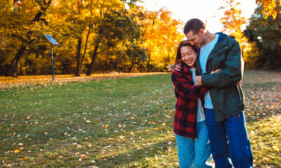 Smiling multiracial couple in love walking in an sunny autumn park.