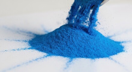 Blue powder being poured, creating a circular pattern on a white surface