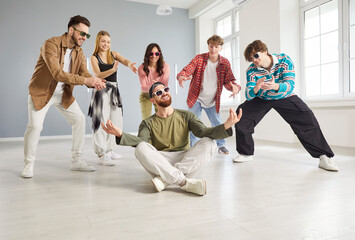 Cool dancer man, group of dancing people actively dancing indoors, moving and posing in studio space, dance class, rehearsal in dynamic pose, enjoying practicing or performing, having fun together