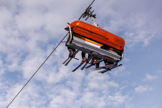 Skiers on modern chairlift against blue sky - Powered by Adobe