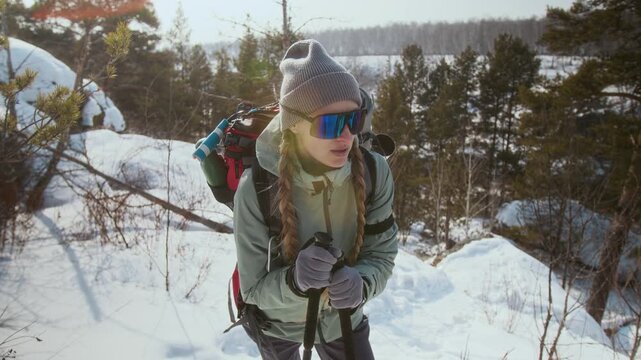 Medium shot of young woman breathing heavily while taking break hiking in winter mountains and walking uphill, copy space