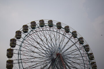 Closeup of multi-coloured Giant Wheel during Dussehra Mela in Delhi, India. Bottom view of Giant Wheel swing. Ferris wheel with colourful cabins during evening time.