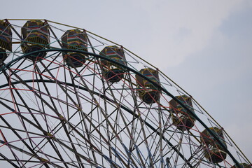 Closeup of multi-coloured Giant Wheel during Dussehra Mela in Delhi, India. Bottom view of Giant Wheel swing. Ferris wheel with colourful cabins during evening time.