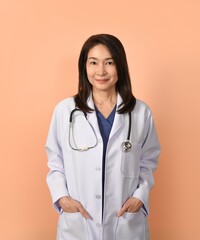 Portrait of asian female doctor in medical uniform with stethoscope on peach color background.