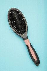 Massage hairbrush on blue background. Vertical photo