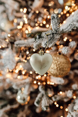 Golden heart and Christmas lights on the snowing tree. Macro and bokeh photo