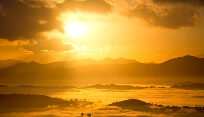 Hazy, sunlit landscape view of distant mountains and low-lying fog under golden sky filled with clouds