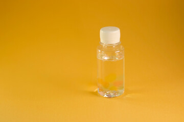 Clear plastic bottle with liquid on and yellow background