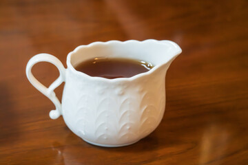 木目調のテーブルに置かれた、メープルシロップが入った白い磁器のピッチャー