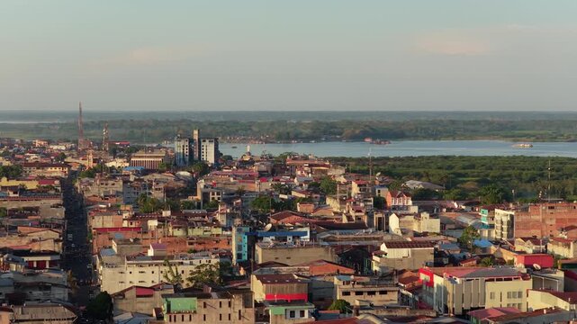 Aerial view of Iquitos, largest city in Peruvian rainforest, with buildings rooftops and Amazon River in the background at sunset