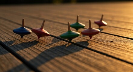 Spinning tops line up on wooden deck, bathed in sunset